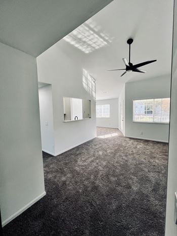 an empty living room with carpet and a ceiling fan